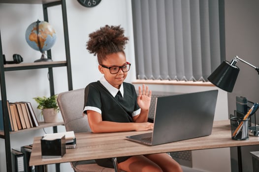 Sitting by the table with laptop. Cute ,female african american student child photo