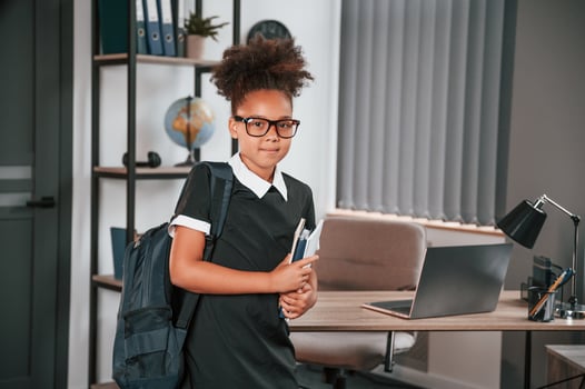 Ready for the school. Cute little girl is standing indoors in domestic room, photo