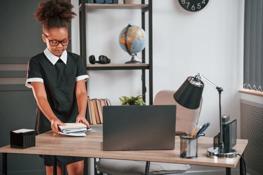 Cute ,little girl in school uniform is standing indoors in domestic room photo