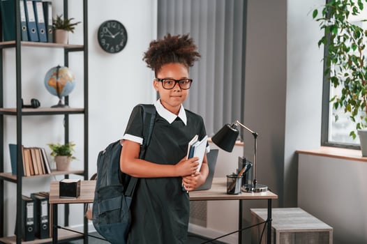 Ready for the school. Cute, little girl is standing ,indoors in domestic room photo