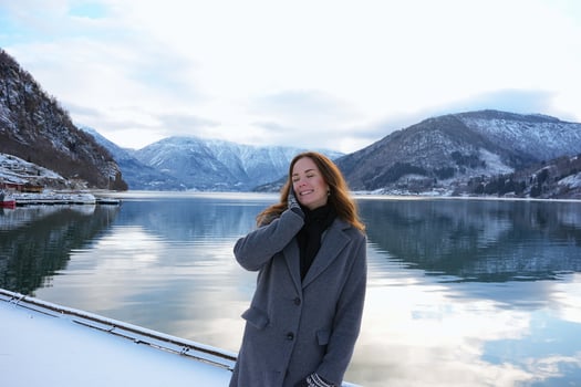 Smiling woman by snowy fjord and mountains in Gaupne, Norway winter scene photo
