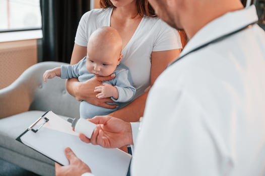With a prescription. Male doctor is taking ,care of woman's newborn baby indoors photo