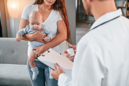 With a prescription. Male doctor ,is taking care of woman's newborn baby indoors photo