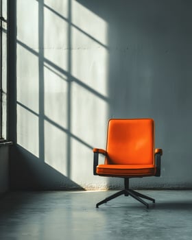 A vibrant orange chair rests alone in a spacious room photo