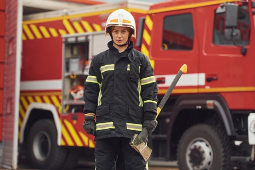Standing with, axe in ,hands against truck. Woman firefighter in uniform is at work in department photo