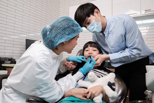 Asian female dentist checks and examines a girl's teeth in dental clinic. photo
