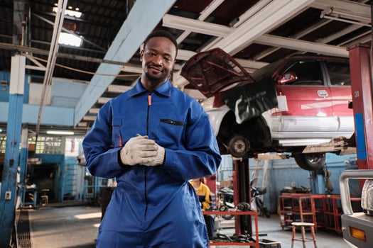 Portrait of confident Black male mechanic, cheerful works and pose with smile in fix car garage, professional engineer maintenance jobs in automotive and transportation industry business. photo
