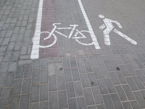 A bicycle lane and pedestrian symbol painted on the pavement, indicating designated paths for cyclists and walkers in an urban setting. photo