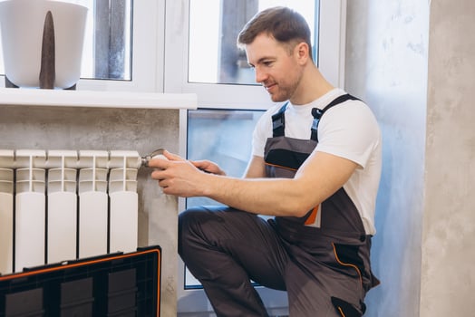 Plumber installing or repairing heating radiator in apartment or home photo