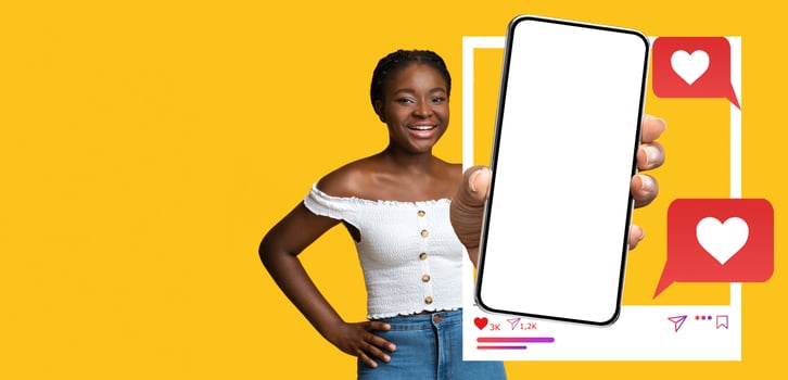 A cheerful influencer smiles while holding a blank smartphone against a vibrant yellow background. The device displays engaging social media icons, suggesting interaction and communication online. photo