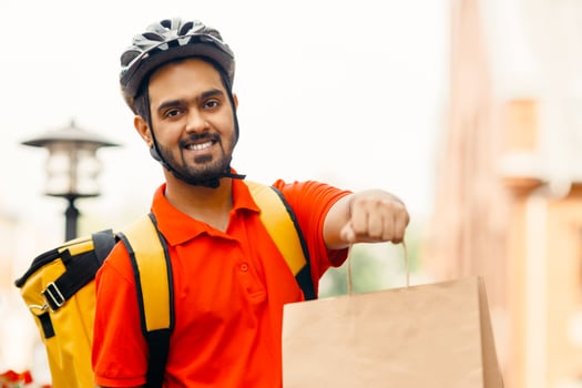 Courier with bicycle delivering packages in city. Online order by courier with yellow backpack on bicycle at street, close up, copy space photo