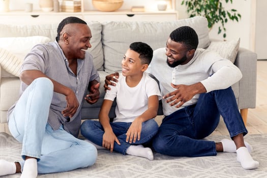 A grandfather, father, and son share laughter and stories in a warm and inviting living space, highlighting meaningful family connections and joyful interactions. photo