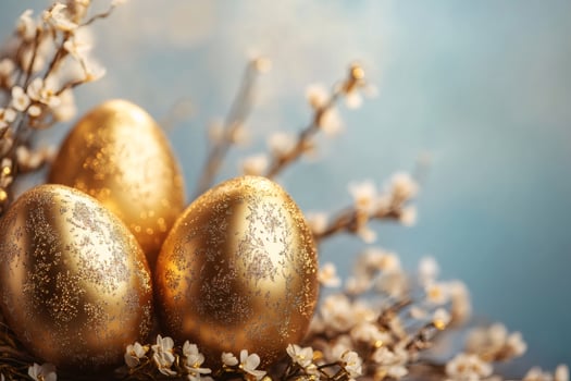 Golden easter eggs decorated with glitter surrounded by cherry blossoms photo