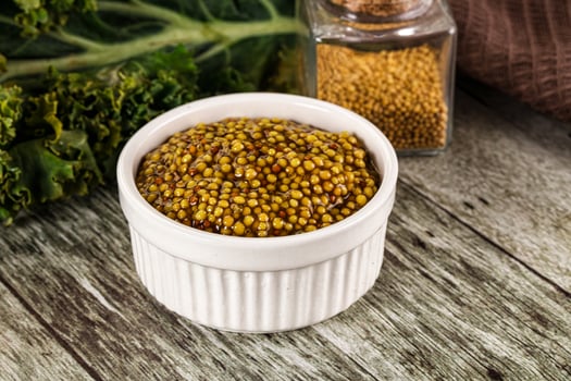 A bowl of mustard and a jar of mustard seeds photo