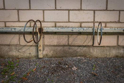 Rusted bike racks against a masonry wall in a quiet urban setting during the late afternoon photo