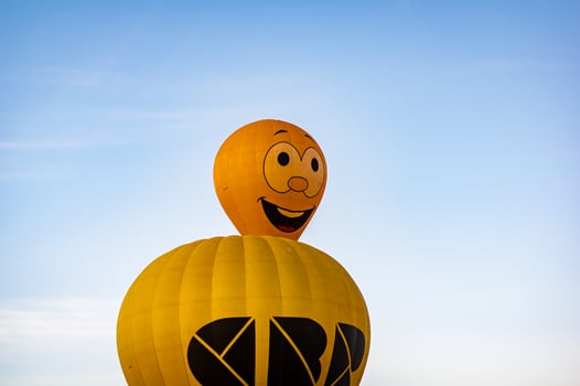 Smiling face hot air balloon above yellow balloon photo