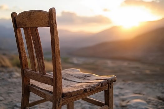 A wooden chair sits on the side of a mountain photo