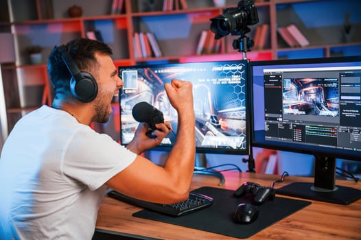 Male game streamer in casual clothes is indoors ,with pc, photo