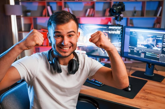 Celebrating victory. Male game, streamer in casual clothes is indoors with pc photo