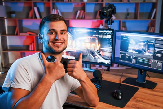 Male ,game streamer in casual clothes is indoors with ,pc photo