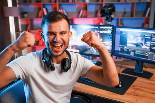 Celebrating victory. Male game streamer in casual, clothes is indoors with pc photo
