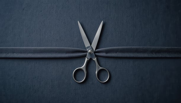 Elegant Scissors Cutting Through Smooth Black Ribbon on Dark Surface photo