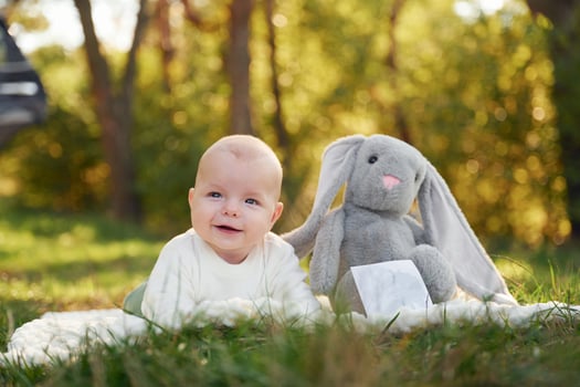 Cute little ,baby is laying down on the ground in the forest with toy near him photo
