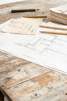 A drafting table showcases an architectural blueprint surrounded by design tools and crumpled sketches photo