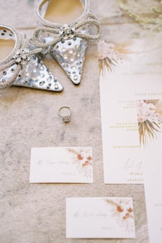 Engagement ring lies next to the invitations and the bride shoes on the carpet photo