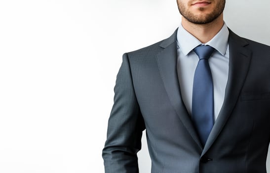 A man in a suit and tie standing in front of a white wall photo