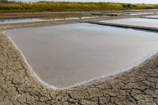 These salt evaporation ponds in the South of France showcase the art of salt harvesting. Sunlight reflects off the shimmering waters, creating a captivating and colorful visual spectacle. photo