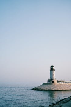 White lighthouse on a breakwater by the sea against a blue sky photo