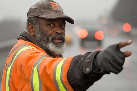A man in an orange vest pointing at something photo