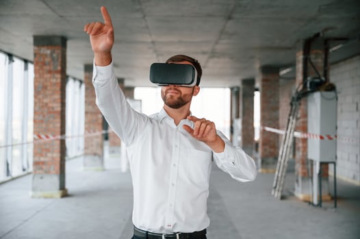 On ,the construction site. Man in formal clothes is playing VR game in the building photo