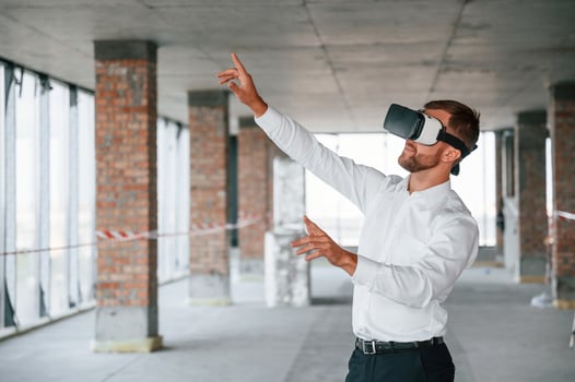 Man in formal clothes is playing VR game, in the building that are on construction site photo
