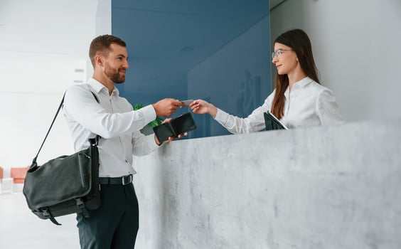 Assistant helping customer. Man in white shirt is ordering a room in the hotel by woman's help photo