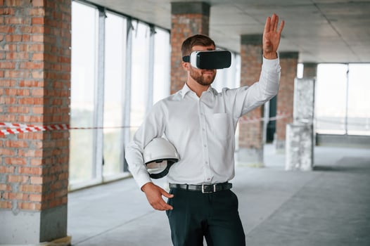 Hands raised ,up. Man in formal clothes is playing VR game in the building that are on construction site photo