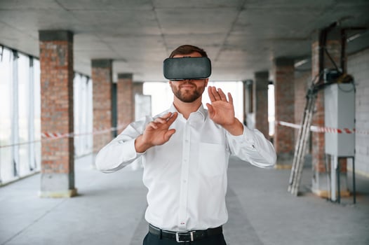 On the construction site. Man in formal clothes is playing VR game in the building. photo