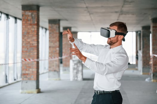 On the construction, site. Man in formal clothes is playing VR game in the building photo