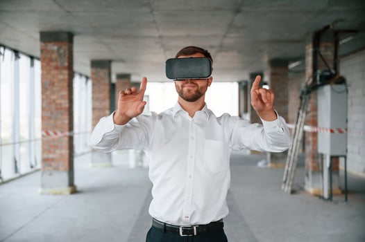 On the construction site. Man in formal, clothes is playing VR game in the building photo
