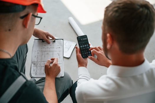 Sitting,, using calculator. Manager with foreman are working on the construction site together photo