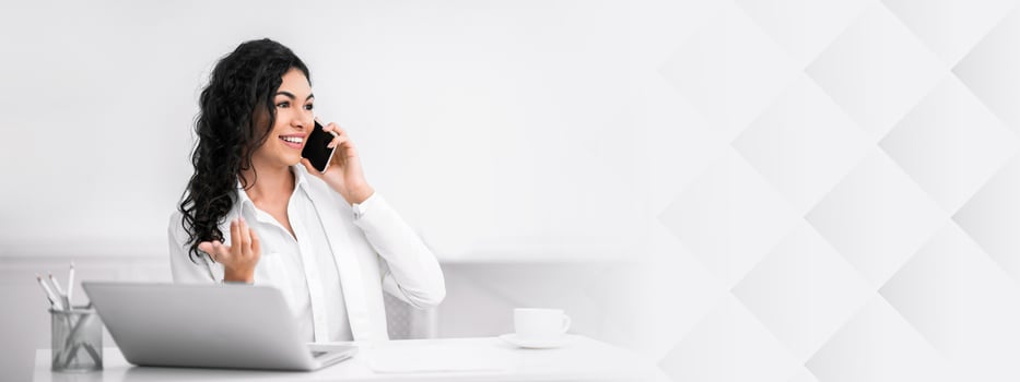 Talkative Lady. Happy latin businesswoman speaking with her friend on mobile phone at work. Panorama, copy space photo