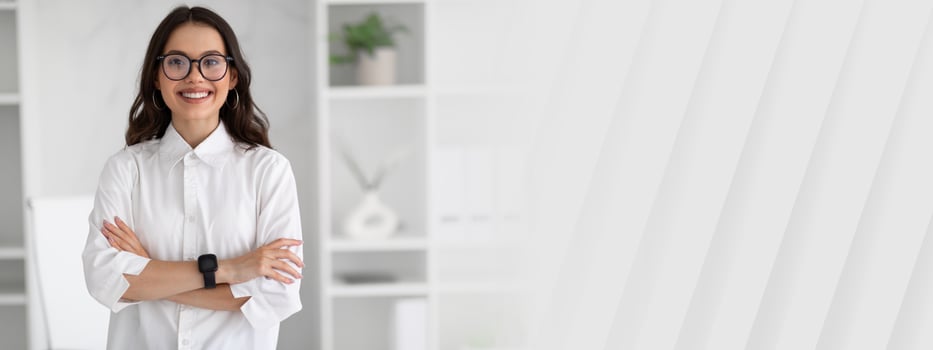 Smiling confident young european woman manager in glasses and white shirt with crossed arms on chest in modern office interior. Businesswoman and successful business, work, lifestyle, ad and offer photo
