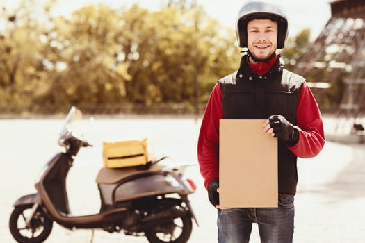Delivery Guy Holding Paper Package Offering Courier Services Standing Near Motorbike Outdoors. Free Space For Text photo