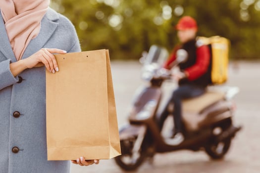 Courier Service. Customer Girl Holding Delivered Food Package Standing Outdoors. Cropped, Selective Focus photo