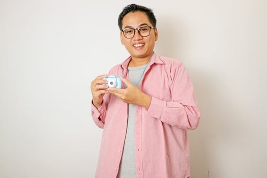 Handsome young photographer poses with smiles and holding professional digital camera in the studio. photo