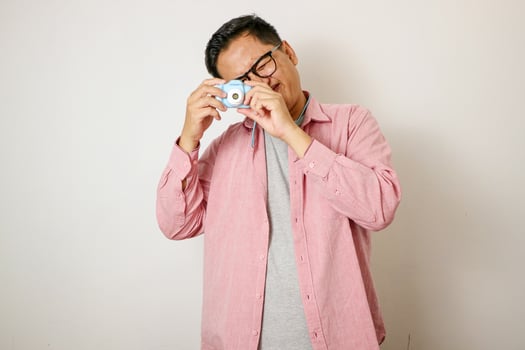 Traveling people concept.Portrait of Asian male backpacker photographer tourist isolated on white. Full body portrait. Taking Pictures with his mirrorrless photo