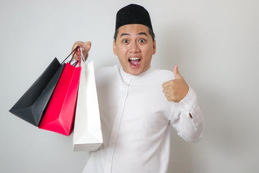 muslim man happy with thumb up hand. online shopping concept in ramadhan kareem for eid mubarak photo