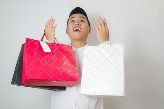 Asian man carrying and showing shopping bags to celebrate Eid Mubarak Idul Fitri photo
