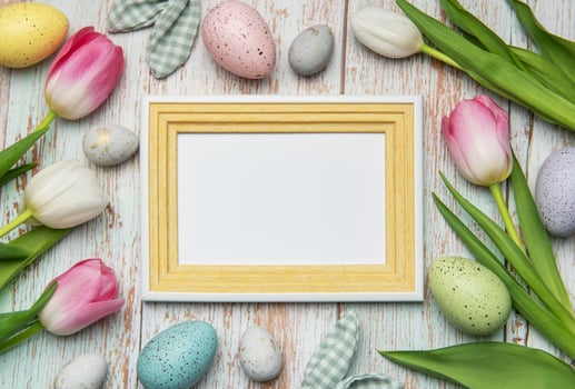 Easter eggs and tulips framing blank picture frame on wooden background photo